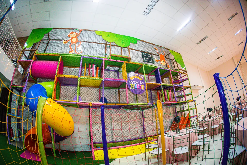 Kid play colorido com escorregadores e tubos ao lado das mesas do salão