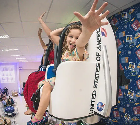 Menina sorrindo em brinquedo com assento temático espacial
